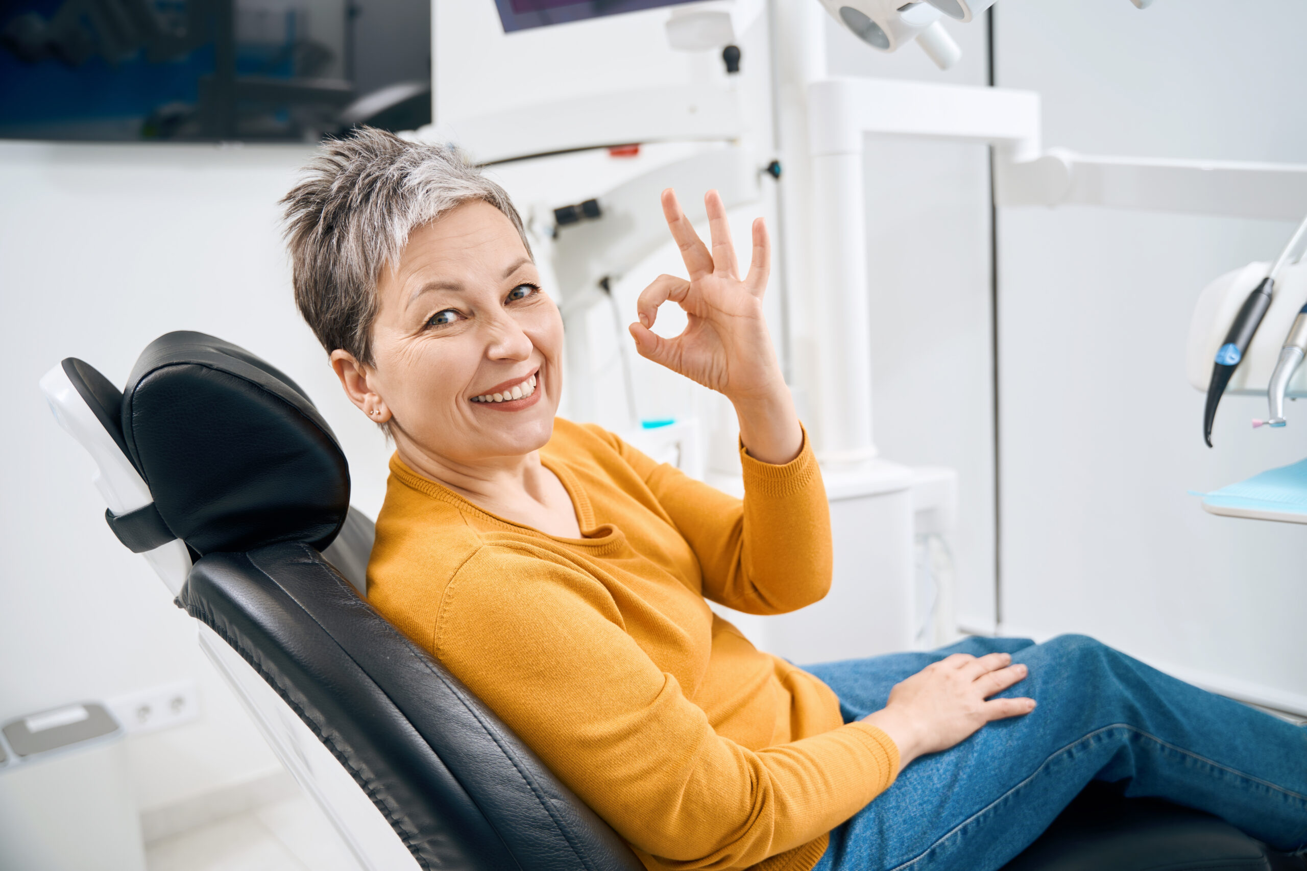 Smiling adult patient sitting in a dental chair after orthodontic care, showing confidence and facial balance improvement