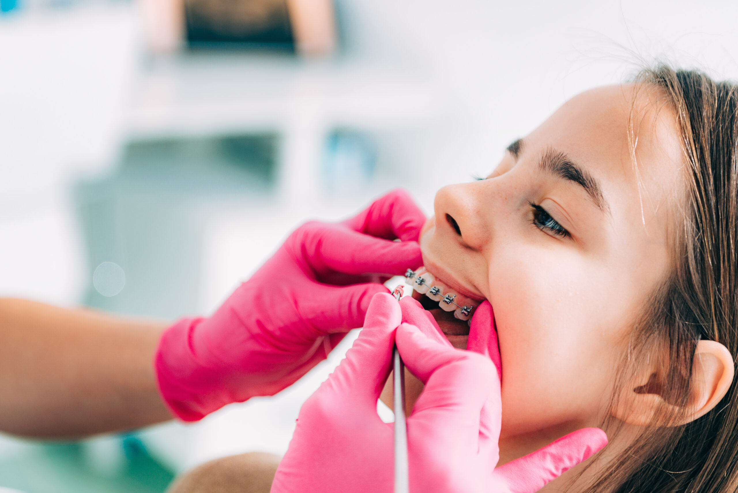 Orthodontist checking girl’s dental braces Dentist gently adjusting braces for a teen patient during an orthodontic visit